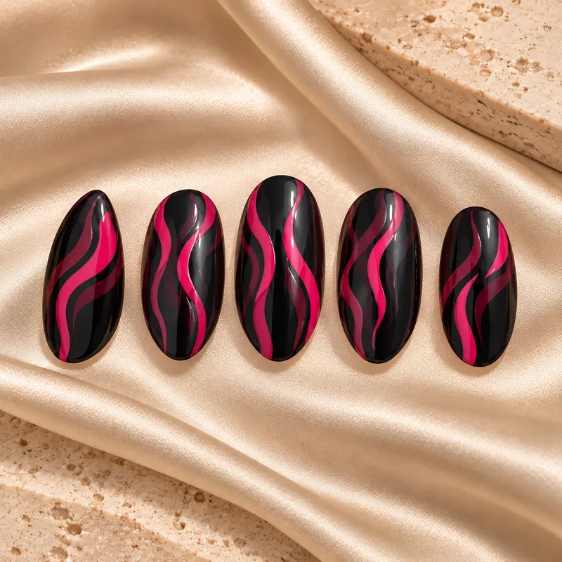 Five glossy black almond nail tips with raspberry-pink ribbons, laid out on champagne silk.